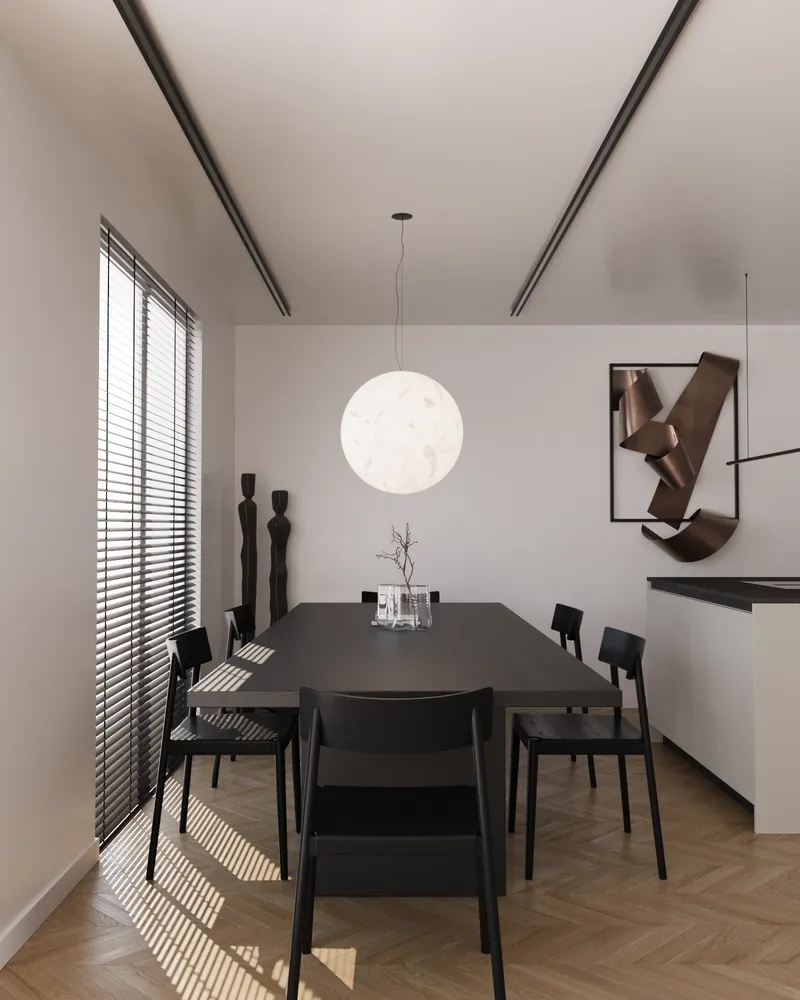 Lune Kitchen: a black dining table under a round paper pendant, beside a cream kitchen with black stone.