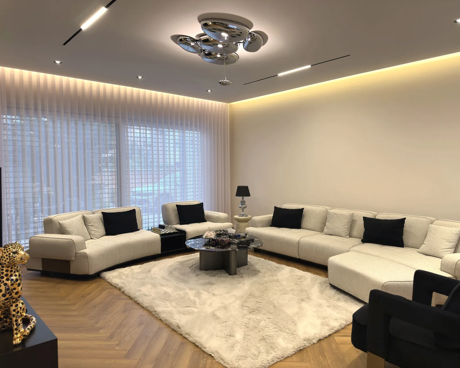 OR House as built: the living room with a sectional sofa, a sculpted ceiling light and floor-length curtains.
